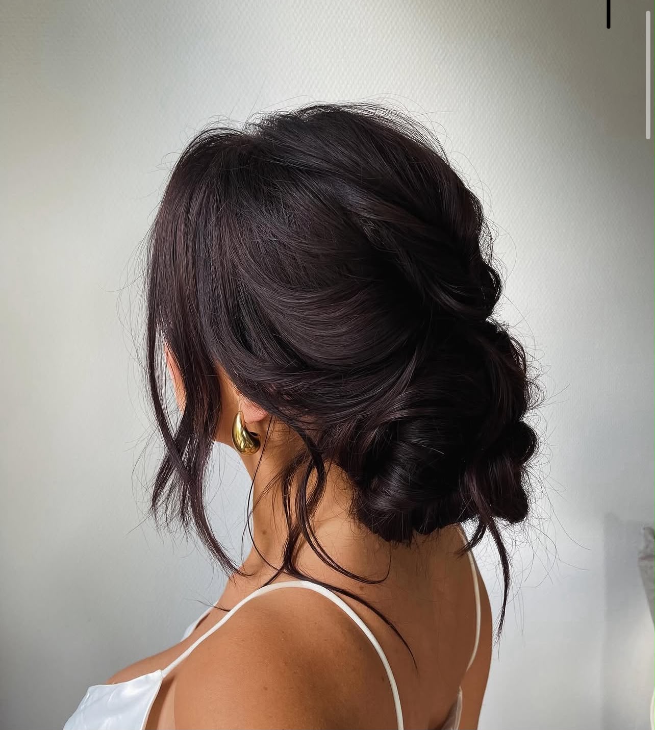 Soft tousled low bun met losse plukken, bridal updo door Quinty