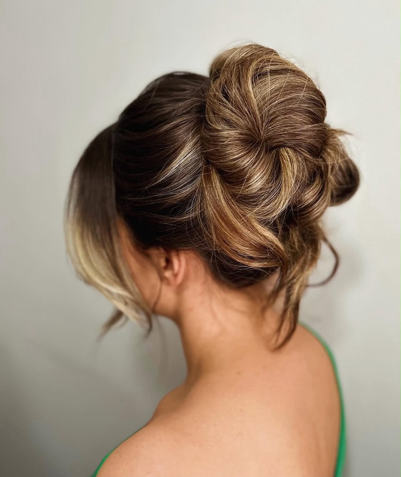Voluminous high bun met losse strengen, editorial bridal updo